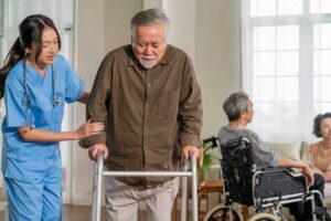 Senior using a handrail in a well-lit assisted living hallway with clear pathways and high-contrast signs