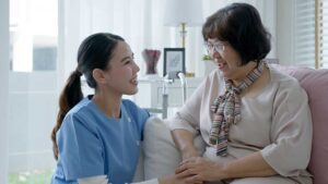 Older adults share a quiet conversation at a table in a bright assisted living common room.
